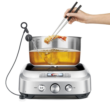 Control Freak Induction Cooktop. deep pan. metal chopstick holding tempure prawn